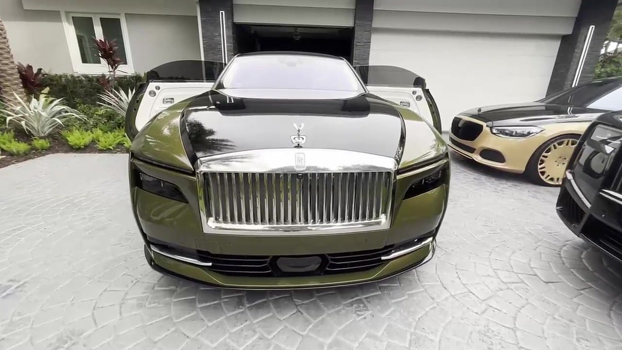 Front three-quarter view of an olive Rolls-Royce Spectre in a driveway